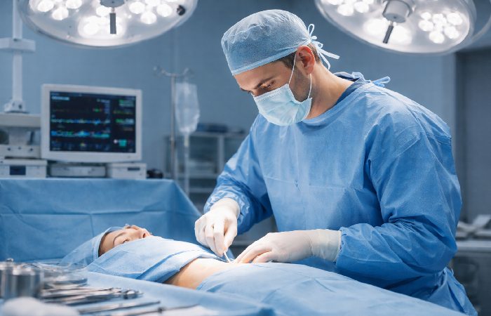 Plastic surgeon performing breast augmentation surgery in accredited operating room