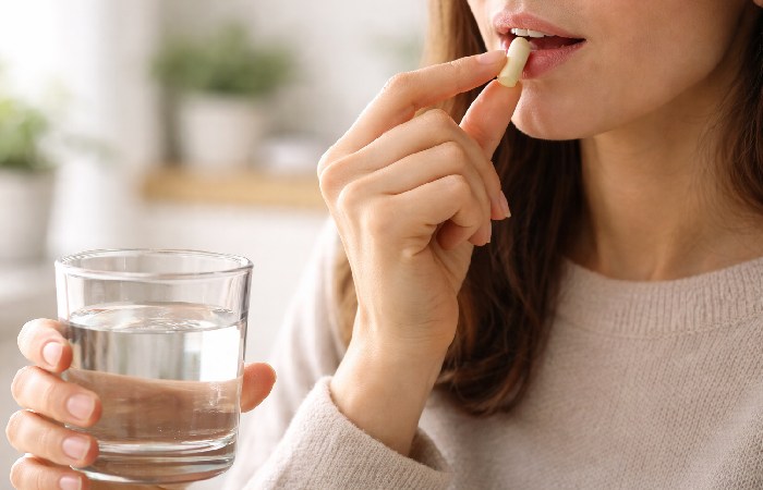 Person taking a vitamin capsule with water to represent safe daily Lipo-B supplementation